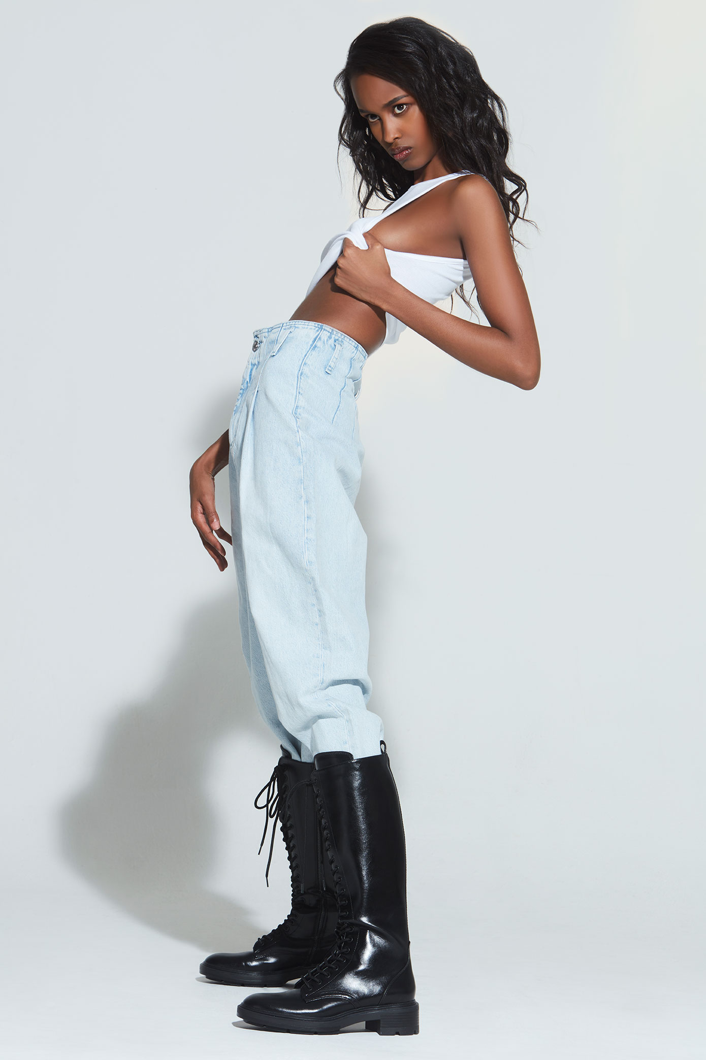 Denim pants, knee high boots and a white tank top. Nasri kills it with her pose. Fashion stylist Brit Lovoi, NYC.